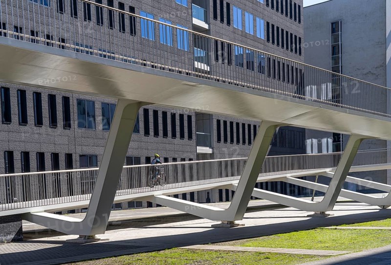 The Parkbruk, cycle and pedestrian bridge in the city centre of Antwerp, crosses a multi-lane city centre road with tram lines and thus connects two lively city districts Kop Spoor Noord and Eilandje, 140 metres of curved ramp on the western side for driving up and down, walking, Belgium, Europe