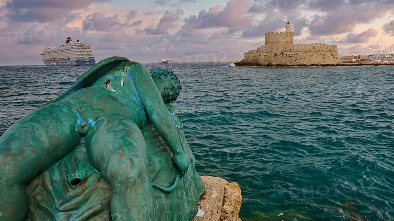 A damaged sculpture looks out over the sea and a fortress during a dramatic sunset, sky exchanged, sculpture Sleeping Eros, cruise ship, Fort of Saint Nikolaos, harbour area, Rhodes Town, Rhodes, Dodecanese, Greek Islands, Greece, Europe