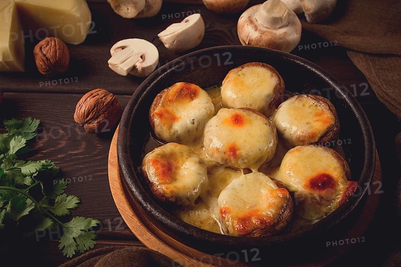 Traditional Georgian dish, appetizer, stuffed mushrooms, Sulguni cheese, baked in a Ketzi clay pan, on a wooden table, close-up, no people