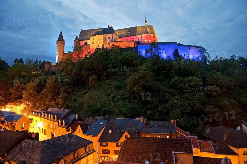Vianden Castle, hilltop castle illuminated in the colours of the Luxembourg flag for the bank holidays, Vianden, Grand Duchy of Luxembourg