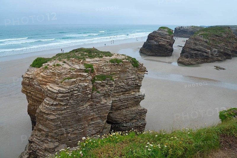 Huge rocks on the beach overlooking the sea. People walking along the shore under a cloudy sky, Praia das Catedrais, Playa de las Catedrales, Cathedral beach, As Catedrais beach, Cantabrian Sea, Ribadeo, Galicia, Galicia, Spain, Europe