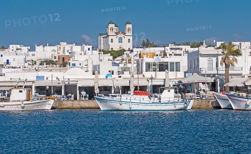 White Greek coastal town with church in the background, fishing boats in the foreground on calm sea with blue sky, Noussa, Paros, Cyclades, Greece, Europe