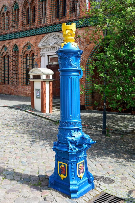 A traditional, blue-painted hydrant on a cobblestone path next to a brick building, water point, Szczecin, West Pomerania, Poland, Europe