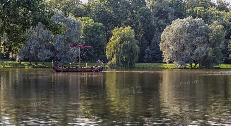 A large wooden boat with tourists floats on the lake. Belarus