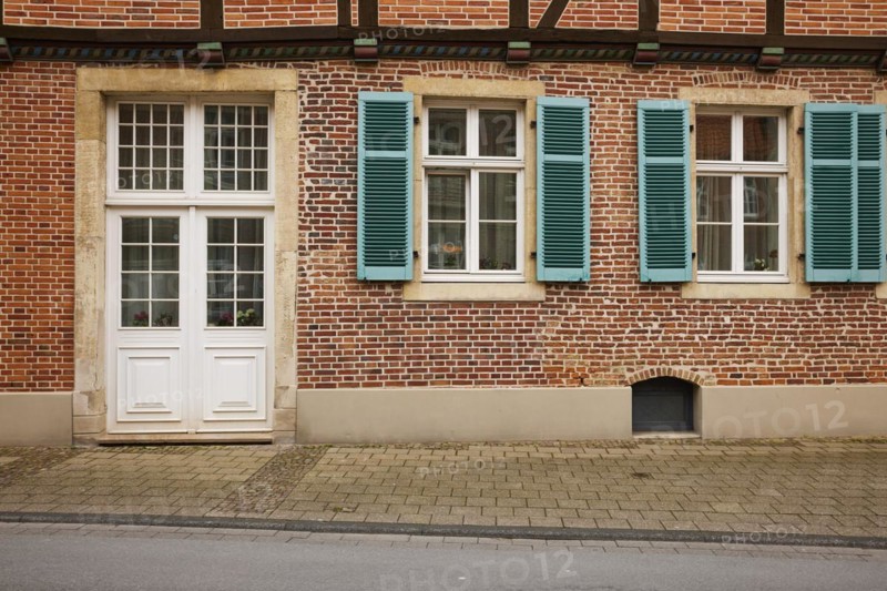 White entrance door and windows with blue-green shutters on a brick house in Warendorf, Warendorf district, North Rhine-Westphalia, Germany, Europe