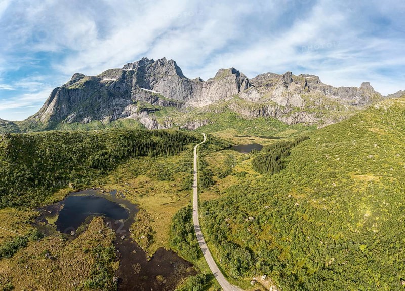 Panoramic aerial view of road in mountain scenery, passing lakes and meadows, road from E10 to village Nusfjord, Lofoten, Norway, Europe