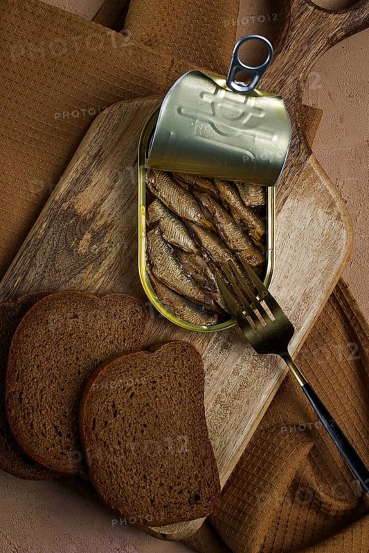 Sprats in butter, with black bread, canned smoked fish, open, close-up, top view, no people