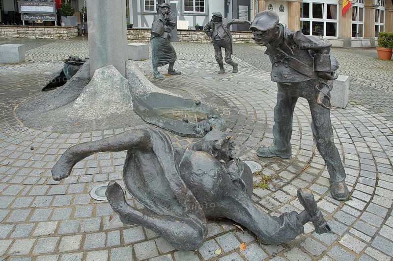 Fools' Fountain by Gero Hellmuth 2010, two sculptures, fools, bronze, lying on the ground, standing, looking down, strange, funny, Swabian-Alemannic, Fasnet, carnival, carnival fountain, fountain, town hall square, Singen, Hohentwiel, Hegau, Baden-Württemberg, Germany, Europe