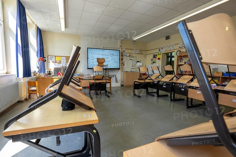 Classroom of a fourth grade, after school, the building is older but in good condition, modern teaching materials, interactive, digital whiteboard