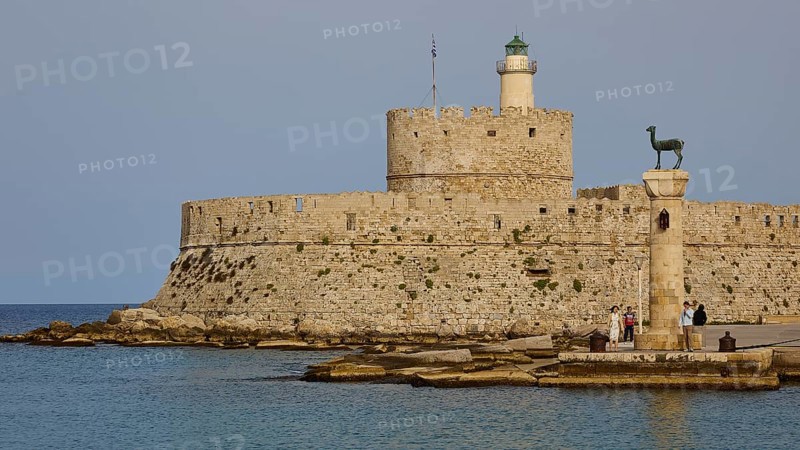 People strolling past a column near an old fortress by the sea, Fort of Saint Nikolaos, European roe deer statue, harbour area, Rhodes Town, Rhodes, Dodecanese, Greek Islands, Greece, Europe