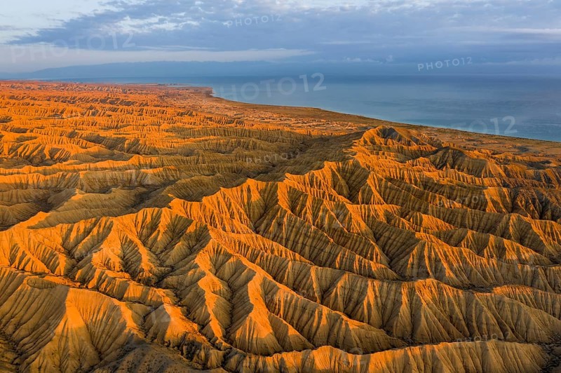 Landscape of eroded hills, badlands at sunset, Lake Issyk Kul in the background, aerial view, Canyon of the Forgotten Rivers, Issyk Kul, Kyrgyzstan, Asia