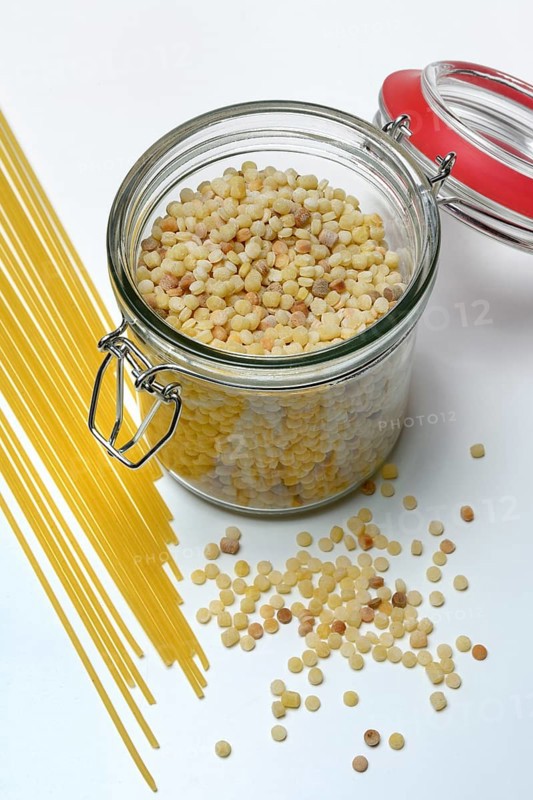 Fregola in wooden spoon and glass container with spaghetti, pasta variety from Sardinia, Italy, Europe