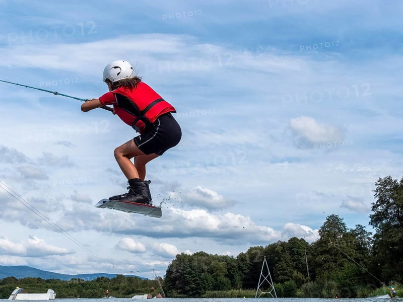 Boy or girl jumping and flying with wakeboard, water sports and water skiing in the wakepark, Stráž pod Ralskem, Czech Republic, Europe