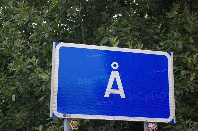 Blue road sign with white frame and the letter Å against a background of dense green foliage, the southernmost town in Lofoten, Moskenes, Nordland, Norway, Europe