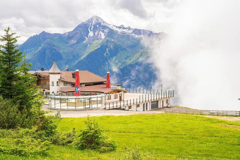 A building on a hill in front of a mountain backdrop with clouds and a green meadow, quiet and idyllic, Penken, Zillertal, Austria, Europe
