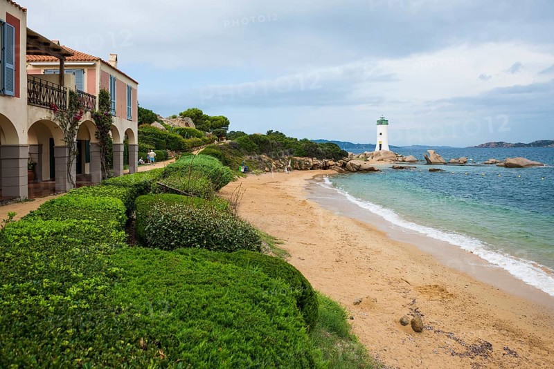 Lighthouse with beach and colourful houses, Spiaggia Porto Faro, Faro di Punta Palau, Palau, Costa Smeralda, Sardinia, Italy, Oceania