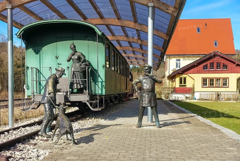 Durlesbach railway station, opened in 1849 and decommissioned in 1984, railway monument, railway memorial, group of figures by the artist René Auer, group of sculptures, scene from the song Auf de schwäbische Eisebahne, billy goat, woman, farmer, conductor, s Bäuerle, Konduktör, s Weible, bronze figures, Königlich Württembergischen Staats-Eisenbahnen, station building at the back right, Durlesbach, Reute, Bad forest lake, Upper Swabia, Baden-Württemberg, Germany, Europe