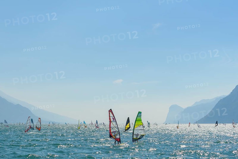 People windsurfing on a sunny day with clear blue skies and mountain backdrop, Lake garda, Torbole, Lake garda, Lago di Garda, Trentino, Italy, Europe