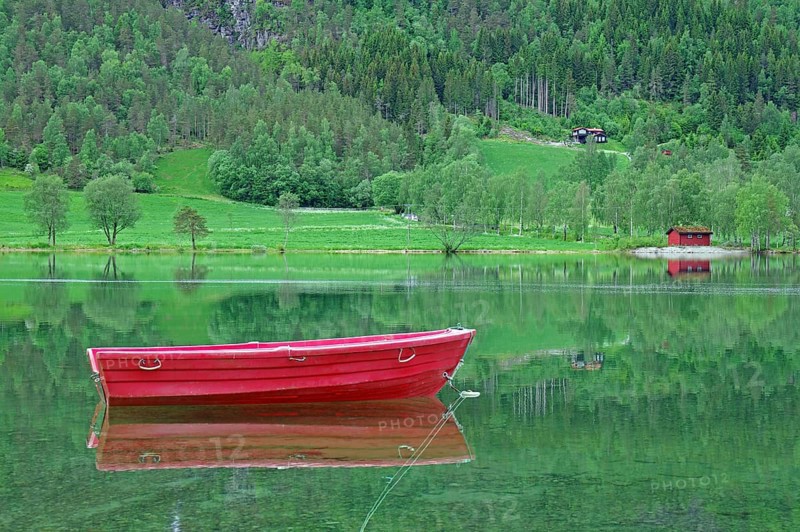A small red boat floats on a calm lake with green surroundings, Stryn, Mindesundet, Fjordland, Norway, Europe
