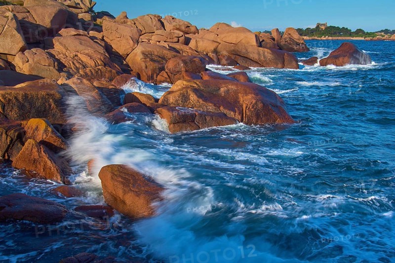 Large rocks on the Granit Rose coast, lapped by the dynamic waves of the blue sea, Ploumanach, Cote De Granit Rose, Cotes-d Armor department, Bretange, France, Europe