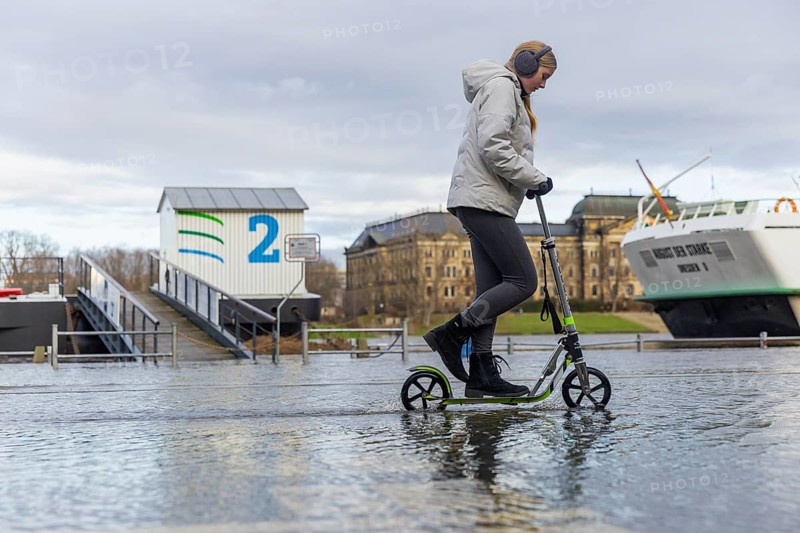 Due to the heavy precipitation in the form of snow and rain, alert level 3 has been declared on the Elbe in Dresden. The maximum level is expected to be 6.37 metres on 29.12.2023. The Terrassenufer was closed due to flooding and the first flood protection barriers were installed. E-scooter rider on the flooded Terrassenufer, Dresden, Saxony, Germany, Europe