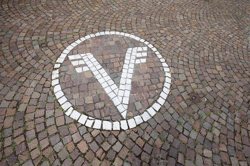 White floor mosaic with Volksbank emblem, paving stones, floor, logo, trademark, bank, sign, V, letter, financial institution, credit institution, white, Zell am Harmersbach, Ortenau, Southern Black Forest, Black Forest, Baden-Württemberg, Germany, Europe