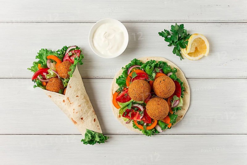 Tortillas, wrapped falafel balls, with fresh vegetables, vegetarian healthy food, on a wooden white background, no people, selective focus