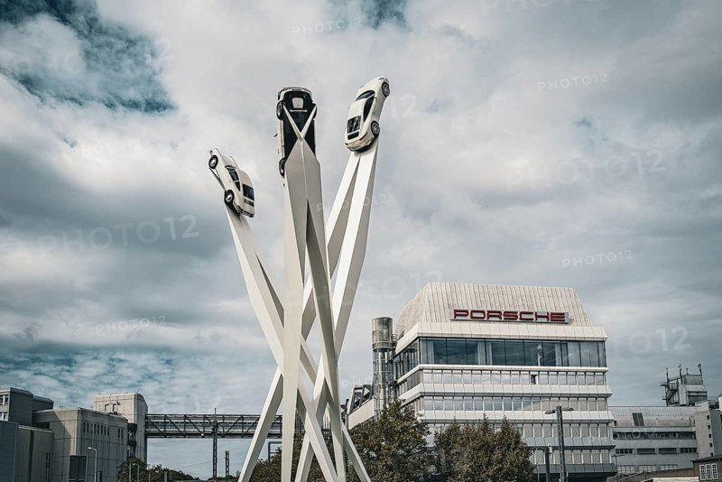 Modern sculpture of cars on high pillars in front of a modern building under a cloudy sky, Porscheplatz with Porsche headquarters, artwork Inspiration 911 by Gerry Judah with Porsche 911 vehicles, Zuffenhausen, Stuttgart, Baden-Württemberg, Germany, Europe