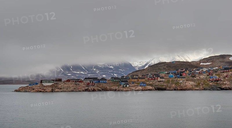 Colourful houses, secluded Arctic Inuit settlement, cloudy coastal landscape against a mountain backdrop, Ittoqqortoormiit, Scoresbysund or Scoresby Sund or Kangertittivaq in Greenlandic, East Greenland, Greenland, North America