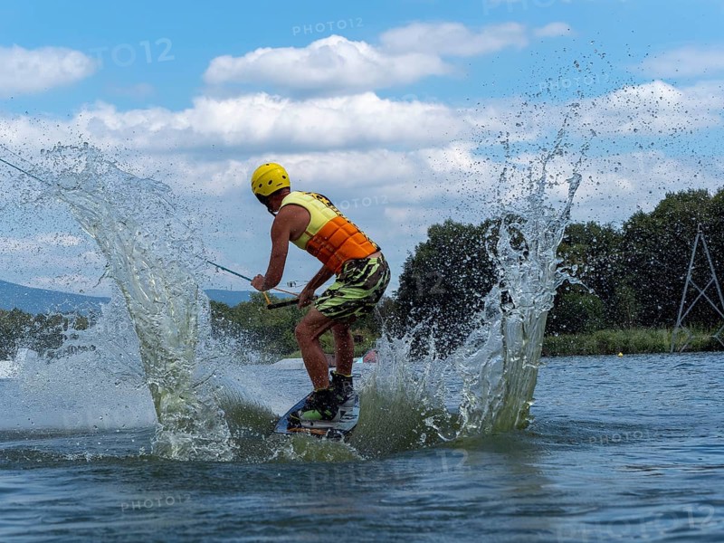 Sporty man with jump with wakeboard, water sports, water skiing and wake park