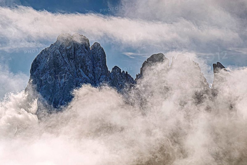 Impressive snow-covered mountain peak, partly covered by clouds, under a clear sky, Val Gardena, South Tyrol, Italy, Europe