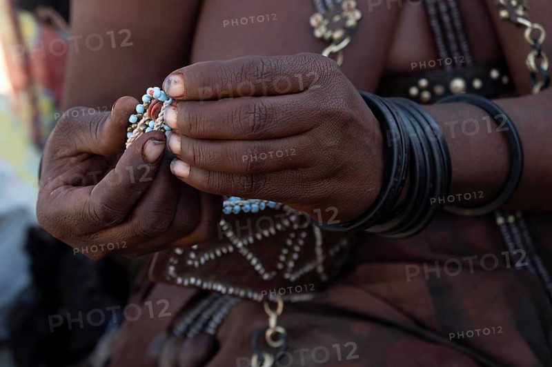 Hands of a Himba woman making bracelets, near Opuwo, Kaokoveld, Kunene, Namibia, Africa