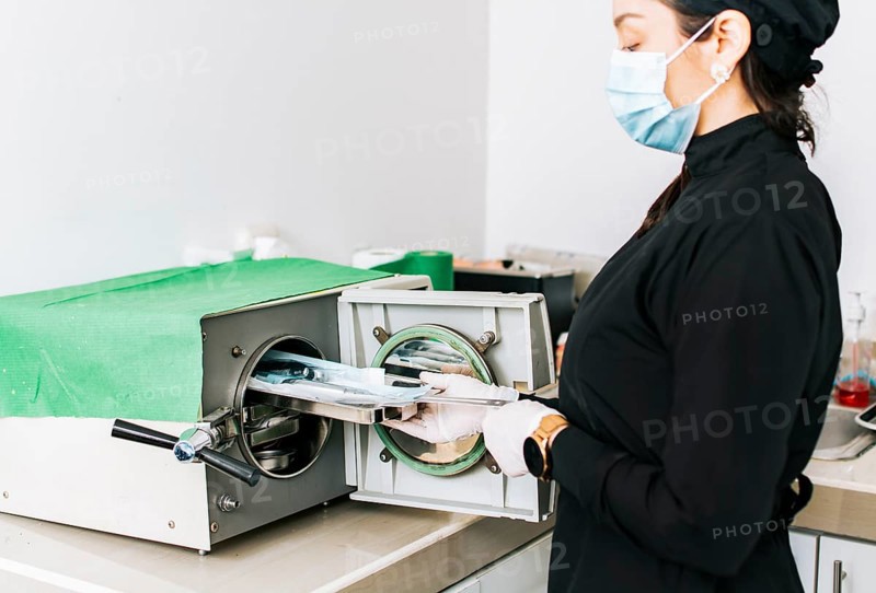 Dentist with a dental sterilizer, A dentist sterilizing his tools, A dentist with a dental autoclave, Close up of a dentist with a steam sterilizer