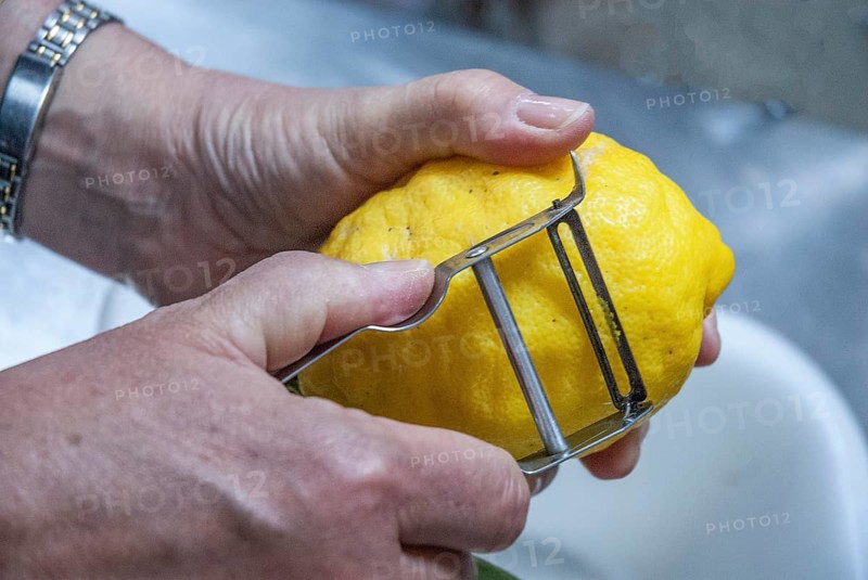 Close-up of two hands peeling a lemon during the making of limoncello, an Italian liqueur in Sorrento, Campania, Italy, Europe