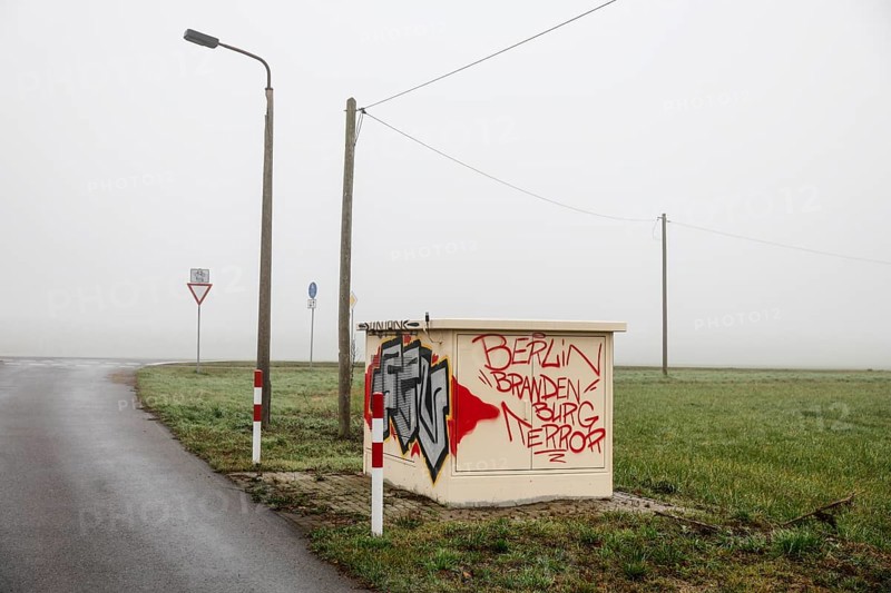 An electricity box sprayed with the phrase Berlin Brandenburg Terror stands at a crossroads on a country road in dense fog, Neugarten, Brandenburg, 06.11.2024, Neugarten, Brandenburg, Germany, Europe