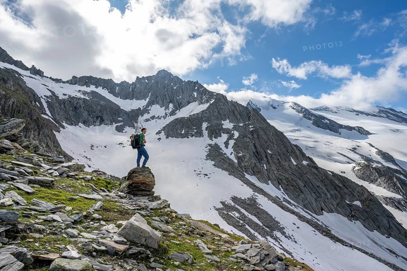 Mountaineer on a rock, rocky mountain peak Furtschaglspitze in the background, glaciated peak Großer Möseler with Furtschaglkees, ascent to Schönbichler Horn, Berliner Höhenweg, Zillertal Alps, Tyrol, Austria, Europe