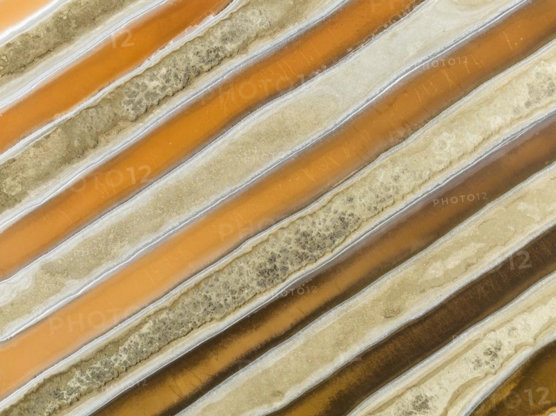 Saline ponds at the salt works near Chiclana de la Frontera. The orange-red colour depends on the level of salinity and is directly caused by the algae Dunaliella salina and brine shrimp. Aerial view. Drone shot. Cádiz province, Andalusia, Spain, Europe