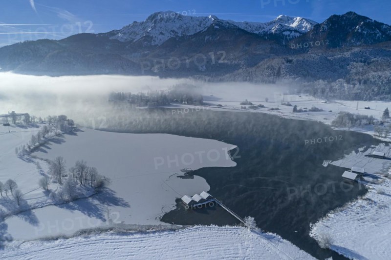 Aerial view of a lake in front of mountains in winter, snow, ice, midday light, view of Herzogstand and Heimgarten, Lake Kochel, foothills of the Alps, Bavaria, Germany, Europe