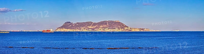 Clear sea with an island in the background and passing ships under a blue sky, Algeciras