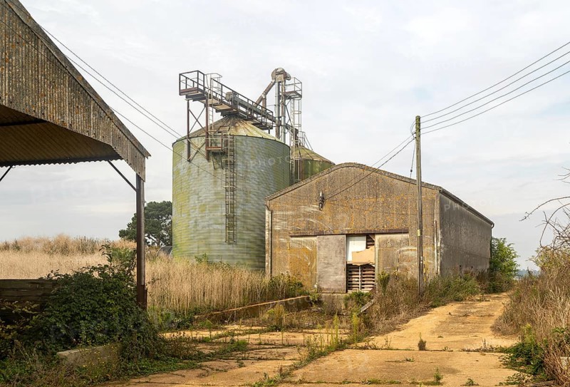 Grain storage silos and asbestos barn in farmyard, Alderton, Suffolk, England, UK