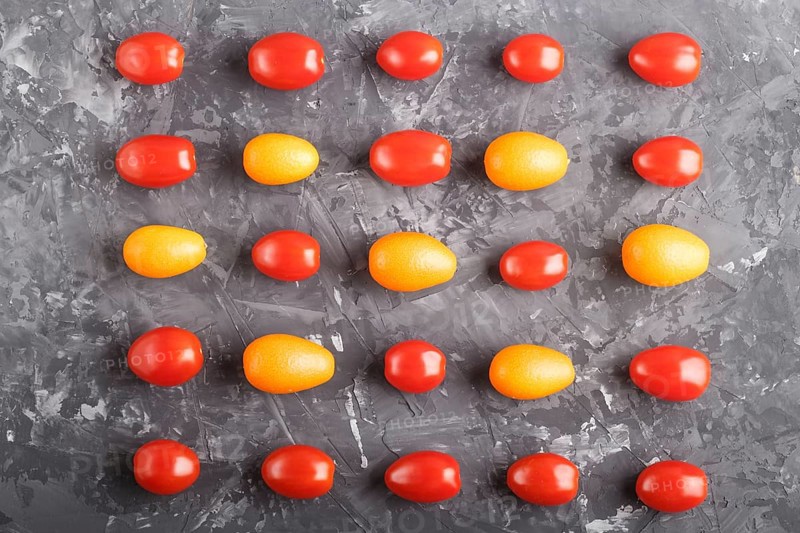 Rows of cherry tomatoes and kumquats on a black concrete background, top view, flat lay. contrast concept