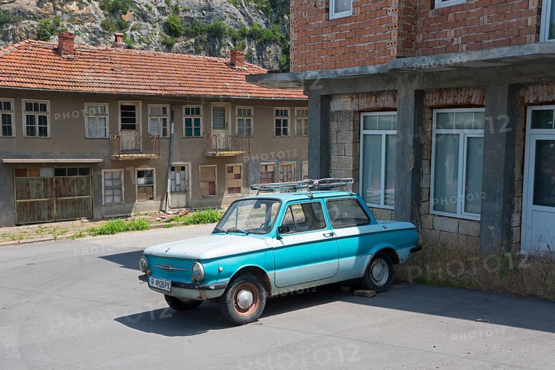 A blue retro car parked in front of dilapidated buildings under a clear sky, Zaporozhets 968, Zaporozh, Sapo, Soviet, today Ukrainian manufacturer Zaporisky Avtomobilebudivny Zavod, SAS, ZAZ, vintage car, Cherven, Ivanovo, Russia, Bulgaria, Europe