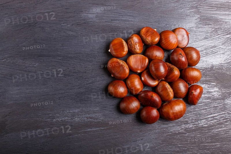 Pile of sweet chestnuts on black wooden background with copy space, top view