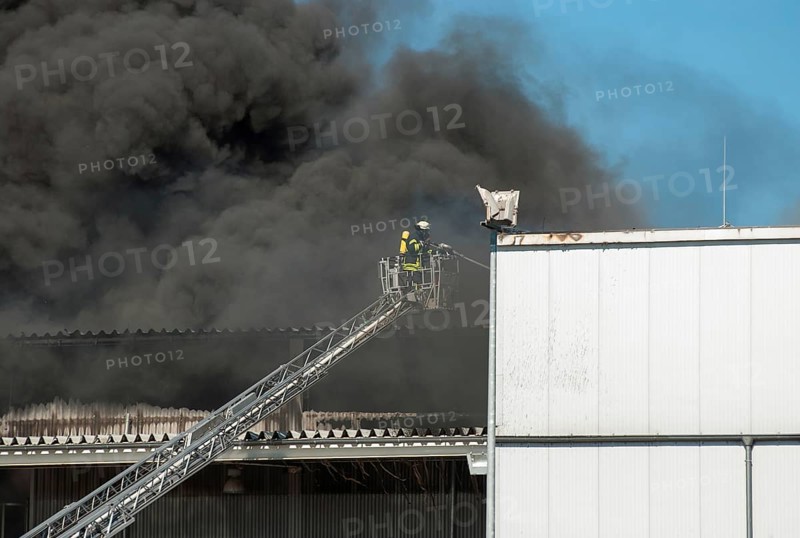 Firefighters in protective clothing in aerial work platform, aerial platform fighting fire in an industrial building, dense smoke at an industrial fire, Lower Saxony, Germany, Europe