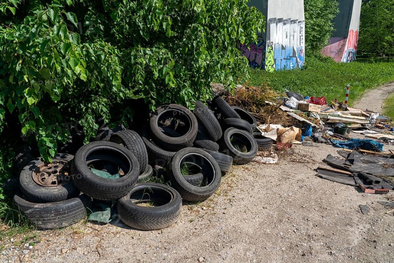 Illegally disposed waste, car tyres, building rubble, household waste, clothing, on a path next to a main road in Bochum, North Rhine-Westphalia, Germany, Europe