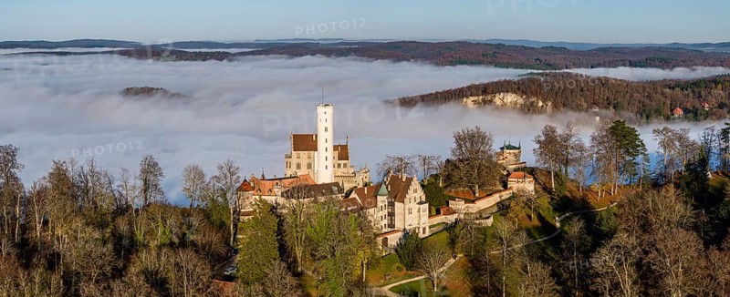 Sunshine in the mountains, fog in the Echaz valley. Lichtenstein Castle in the Swabian Alb. The fairytale castle of Württemberg is a 19th century castle built in the historicist style. Aerial view, panoramic photo. Lichtenstein, Baden-Württemberg, Germany, Europe