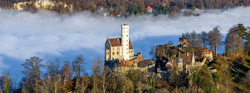 Sunshine in the mountains, fog in the Echaz valley. Lichtenstein Castle in the Swabian Alb. The fairytale castle of Württemberg is a 19th century castle built in the historicist style. Aerial view, panoramic photo. Lichtenstein, Baden-Württemberg, Germany, Europe