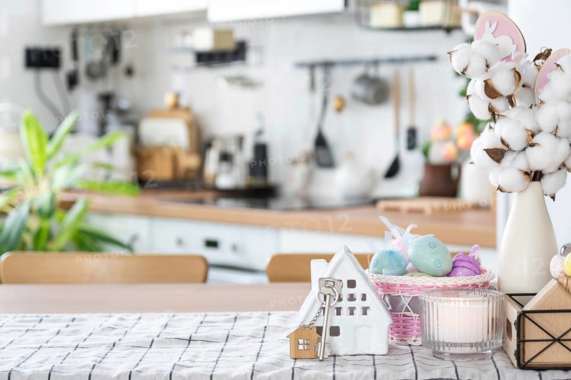 Key to house of cozy home with Easter decor with rabbit and eggs on table of kitchen. Building, design, project, moving to new house, mortgage, insurance, rent and purchase real estate