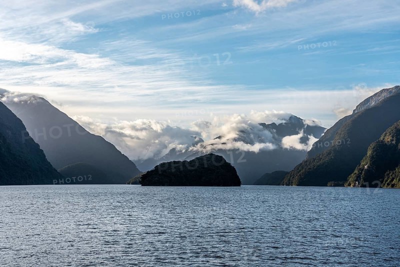 Sun rising over Doubtful Sound, Clouds hanging low on the mountains, South Island of New Zealand