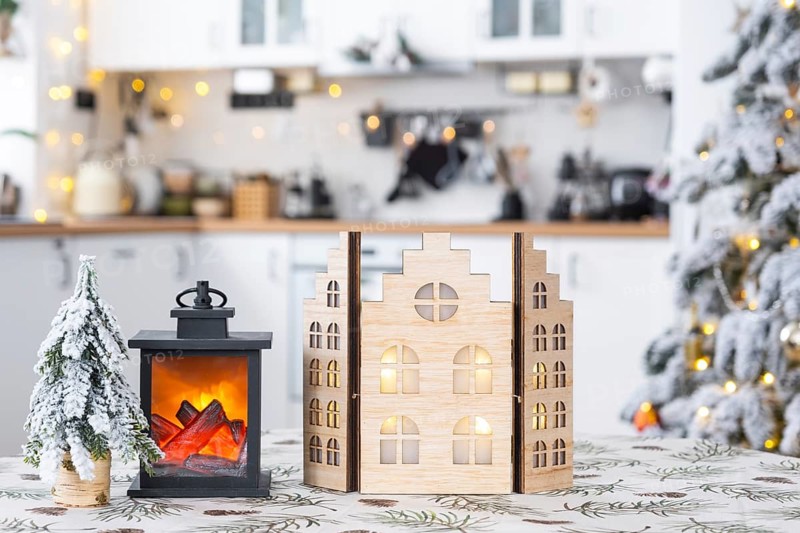 Cozy Christmas decor tiny house of small size on table of festive white modern kitchen. Gift for New Year. Insurance, moving to new house, mortgage, rent and purchase real estate